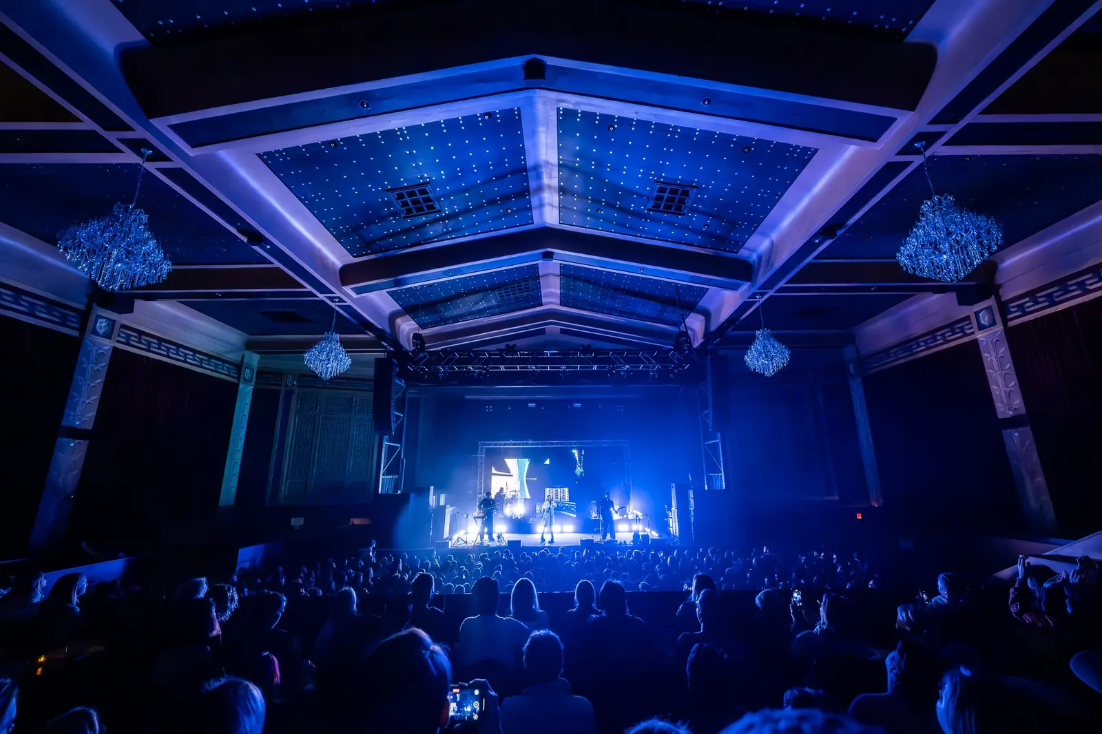 A blue-lit venue seen from the audience